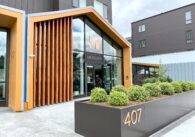 Exterior of building with floor to ceiling glass entrance and name "Meridian" over the doorway, and address number 407 on a planter in front of entrance