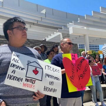 Protesters stand with signs outside San Jose City Hall