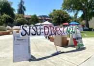 Multiple tents behind a large banner reading "SJSU: Divest Now."