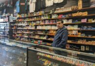 A man standing in a smokeshop, surrounded by shelves with drug paraphernalia