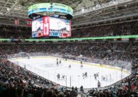Large hockey arena with fans watching players on the ice.