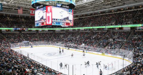 Large hockey arena with fans watching players on the ice.