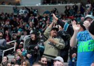 Ice Hockey fans at a game standing and cheering.