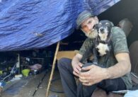 man sits in tent with his dog