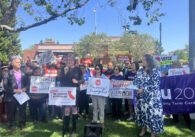 A group of people holding signs outside
