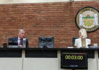 A man and woman sitting at a dais at a government meeting