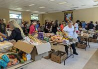 Older adults shuffle around tables piled with food