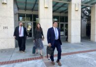 Three people leaving a building. Two men and one woman.