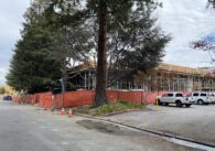 Orange constructionfences surrounding a partially-built building with metal and concrete frame exposed