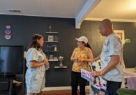 A Vietnamese woman stands chatting with a Vietnamese couple in a house