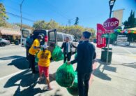 A group of people pass bags of trash into a van