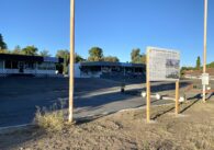 Two vacant single-floor retail spaces and empty parking lot with a city notice of