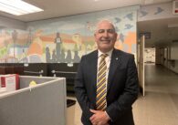 A man in a suit stands inside a school district office