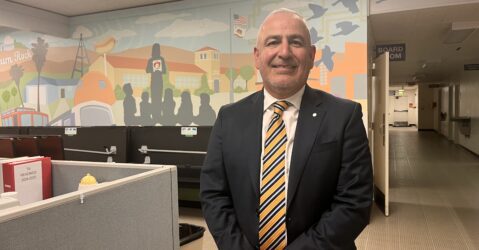 A man in a suit stands inside a school district office