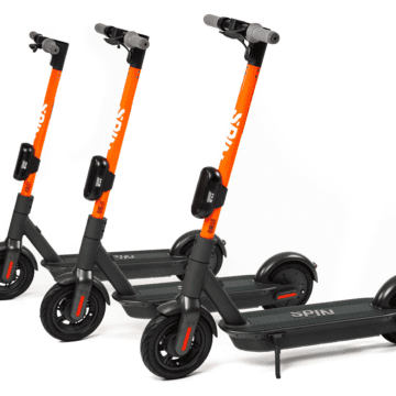 Spin brand e-scooters parked upright. Photo courtesy of Spin.