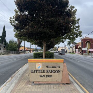 A neighborhood sign in the median of a street with a tree behind it in San Jose, California