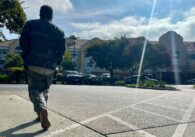 A man walking on the sidewalk outside an apartment building