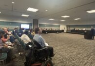 A crowd of people sitting inside in chairs