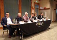 Six Cupertino council candidates sit at a table covered in a San José Spotlight tablecloth