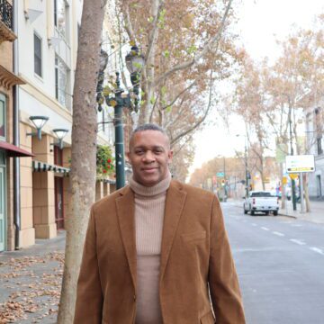 A man in a turtleneck and blazer waking outside in San Jose, California