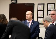 Man in suit standing and looking off camera with four people around him