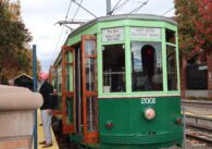 A man stands next to a trolley at an outdoor train station