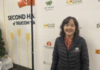 A woman stands smiling at the camera