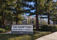 The outside of a gated apartment complex in Cupertino with a sign that reads, "The Hamptons Apartment Homes"