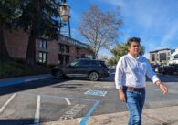 A young Mexican man walks in a small downtown area.