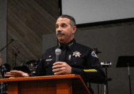 The chief of police in San Jose stands at a podium holding a microphone