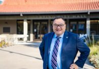 A man in a suit stands outside a city hall