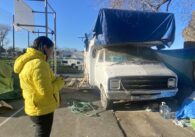 A woman stands outside next to an RV that someone else is living in