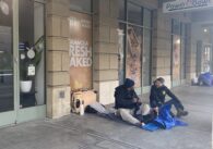 Two people sitting on the sidewalk in downtown San Jose