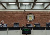 Two men and one woman sit behind a council dais in front of a sign that says "Town of Los Gatos."