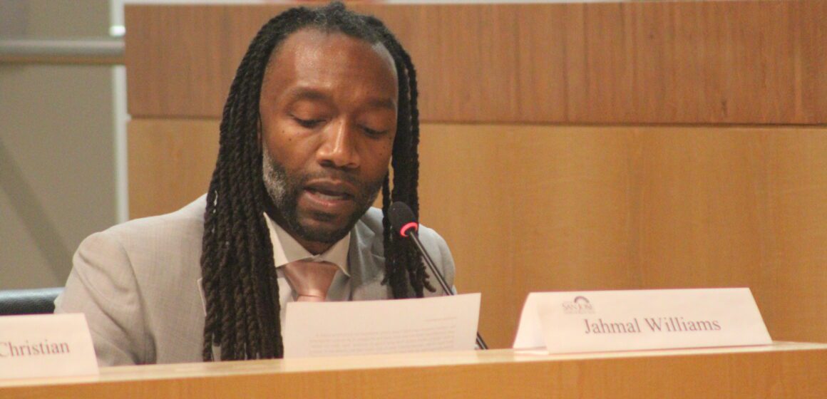 A Black man sitting at a government meeting in San Jose, California