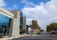 A two-story office building in a parking lot of office buildings.