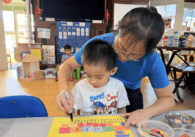 A woman and child make crafts at a day care center