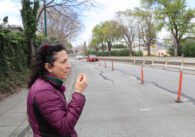 Woman in puffer jacket walks in blocked pedestrian lane while cars drive on the open lanes