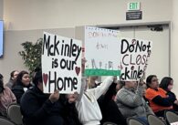 People holding protest signs at a school board meeting