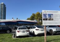 A parking lot with a development project sign in the foreground