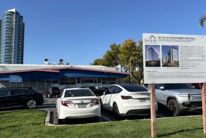 A parking lot with a development project sign in the foreground