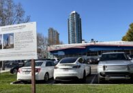 A parking lot with a development project sign in the foreground