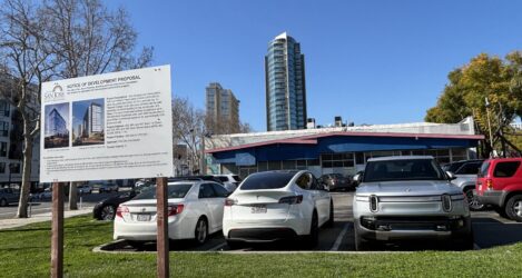 Un estacionamiento con un cartel de proyecto de desarrollo en primer plano.