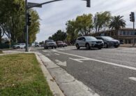 A painted bike lane on the side of an asphalt road with cars driving past.