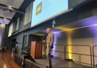 A man in a suit stands on a stage