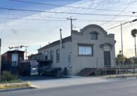 A picture of a house on the corner of a San Jose street near a body of water.