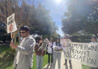 A group of people carry protest signs outside