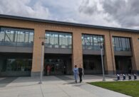 The outside of the Cupertino Library, a two-story building with tan bricks and windows looking into the second floor.