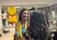 A woman smiling while talking to another woman