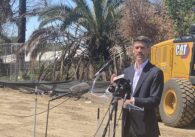A man in a suit speaks at a podium at a construction site in San Jose